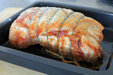 A rolled roast pork joint in a roasting tray.