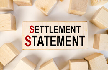 settlement statement, TEXT on a block of wood against a light background