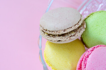 Group of traditional biscuits called macarons made of almond flour with different fillings in translucent glass plate