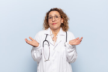 hispanic middle age woman feeling puzzled and confused, doubting, weighting or choosing different...