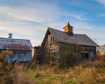 evening sun lights up the cupola on an abandoned barn
