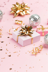 Gold and silver decorations, mirror disco balls, gifts on pastel pink paper background.