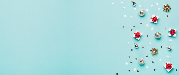 Christmas gold and silver decorations, mirror disco balls, gifts on pastel blue paper background.