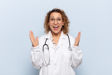 hispanic middle age woman feeling happy, excited, surprised or shocked, smiling and astonished at something unbelievable