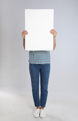 Woman holding blank poster on light grey background