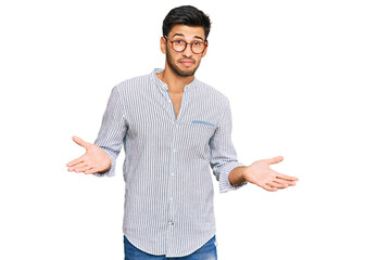 Young handsome man wearing casual clothes and glasses clueless and confused expression with arms...