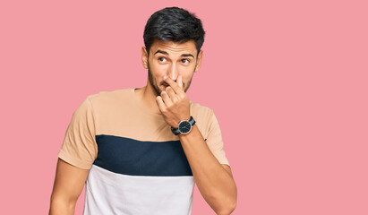Young handsome man wearing casual clothes smelling something stinky and disgusting, intolerable...