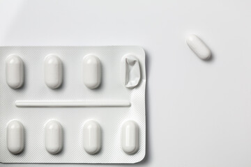 Blister pack of pills with one pressed out onto isolated white surface. Medicine pills used medication simple