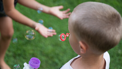 Toddler boy blowing soup bubbles outside
