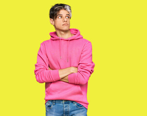 Young hispanic man wearing casual pink sweatshirt smiling looking to the side and staring away thinking.