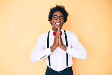 Handsome african american man with afro hair wearing hipster elegant look praying with hands together asking for forgiveness smiling confident.