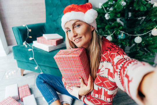 A Young Blonde In A Santa Hat And A Christmas Sweater Makes A Festive Selfie For Social Networks.