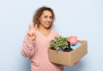 hispanic middle age woman smiling and looking friendly, showing number three or third with hand...
