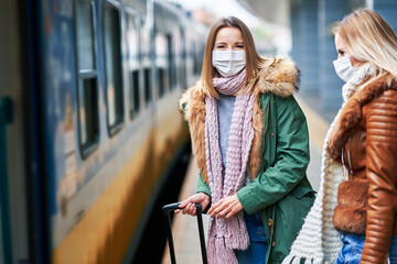 Two women at train station wearing masks due to covid-19 restrictions