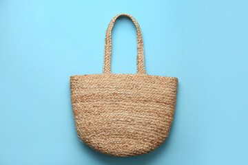 Elegant woman's straw bag on light blue background, top view