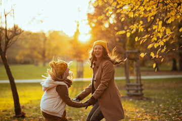 mom and child outdoors on city park in autumn having fun time