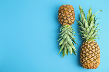 Fresh ripe juicy pineapples on light blue background, flat lay. Space for text