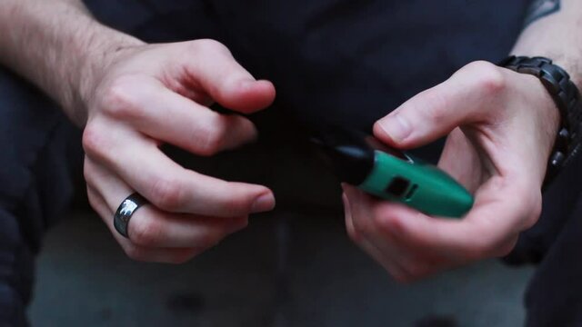 Close up of a guy holding a green vape manly hands