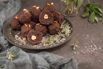 Dark chocolate truffles with hazelnuts on plate.