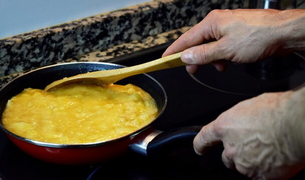 hombre cocinando, terminando una tortilla de patata espa&ntilde;ola