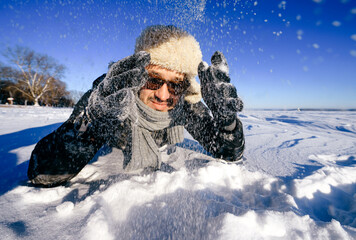 Fototapeta na wymiar Happy man in sunglasses playing with snow outdoors