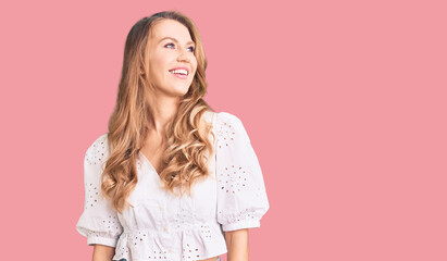 Obraz premium Young caucasian woman with blond hair wearing elegant summer tshirt looking away to side with smile on face, natural expression. laughing confident.
