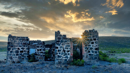 Sunset creates a sunburst seen through stone ruins Idaho desert