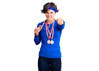 Beautiful young woman with short hair wearing winner medals annoyed and frustrated shouting with anger, yelling crazy with anger and hand raised