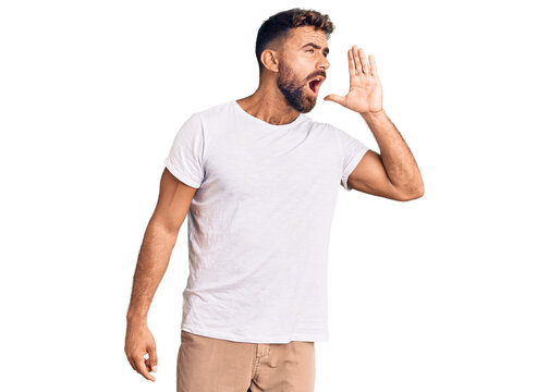Young hispanic man wearing casual white tshirt shouting and screaming loud to side with hand on mouth. communication concept.