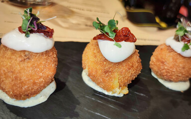 Breaded potato ball stuffed with lamb stir-fry with lime mayonnaise, basil cream and chopped pomodori, Spain