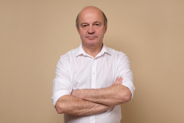 Elegant senior bald man smiling confident at camera. Positive facial human emotion. Studio shot