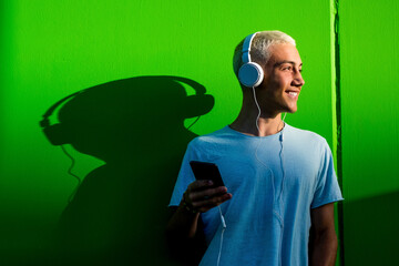 portrait of one teenager or young man listening to music using headphones - millennial having fun...