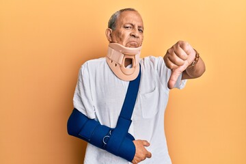 Handsome mature senior man wearing cervical collar and arm on sling looking unhappy and angry...