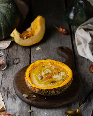 Pumpkin cream soup served in pumpkin, wooden old table, dark photo