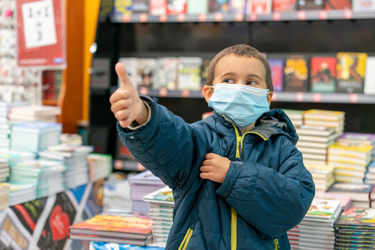 Boy in medical mask at bookstore. young boy chooses books in a bookshop. boy wear a protective mask In a bookstore. Concept of life And protect yourself from the coronavirus outbreak