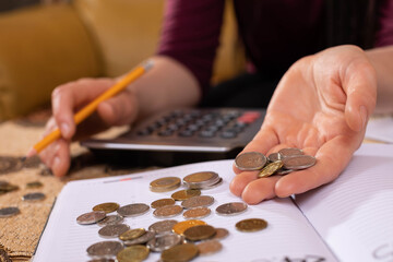 There are coins on the calendar and a young woman counts them because she wants to check if she has enough money to spend by the end of the month.