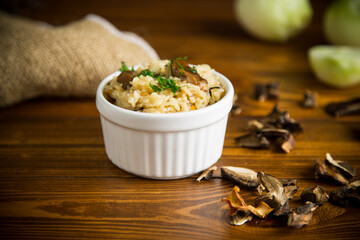 cooked rice with dried forest mushrooms on a wooden table