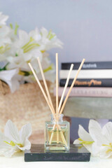 reed diffuser essential aromatherapy oil in decorative materials with white flowers and books on the background