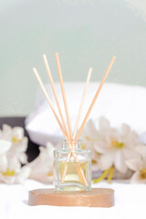 Fototapeta na wymiar reed diffuser essential aromatherapy oil in the bedroom decoration with a white flowers and pillow in the background
