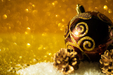 Christmas background: Christmas ball decorated with golden glitter, small golden pine cone, golden glitter background, selective focus, free copy space
