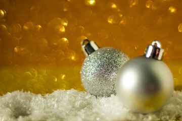 Christmas background: Christmas ball decorated with silver glitter, golden glitter background, selective focus, free copy space