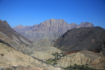 View of the green valley among the arid mountains of different rocks and colors, Wadi Bani Awf, Al Rustaq, South Batinah Governorate of Oman