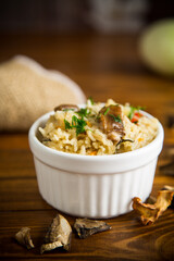 cooked rice with dried forest mushrooms on a wooden table