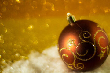Christmas background: Christmas ball decorated with golden glitter, golden glitter background, selective focus, free copy space
