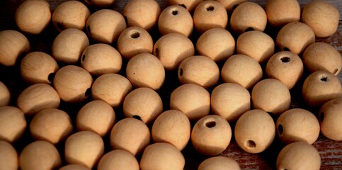 Many round wood beads on the table. Unfinished natural wooden ball beads