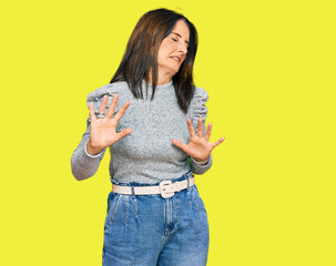 Middle age brunette woman wearing casual clothes disgusted expression, displeased and fearful doing...