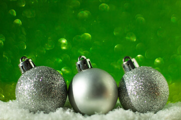 Minimalist Christmas concept: silver Christmas balls in a row, green glitter background, selective focus, free copy space