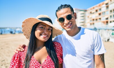 Obraz premium Young latin couple smiling happy and hugging at the beach.