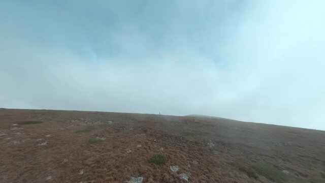 Man operating FPV drone pilot with remote control and goggles in foggy mountain. Cyclist using sport drone to explore mountainous terrain in extreme travel. Extreme mountain biking and shooting.
