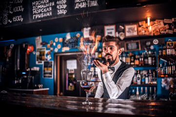 Experienced bartending decorates colorful concoction while standing near the bar counter in pub